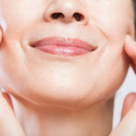 woman smiling while touching her supple face cheeks