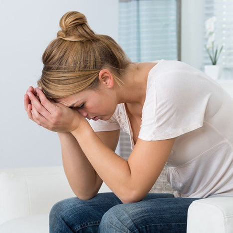 young woman leaning on her hands holding her head in pain