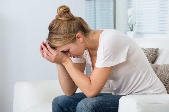 young woman leaning on her hands holding her head in pain