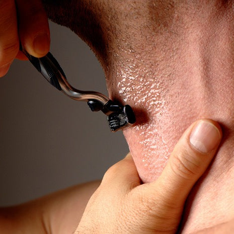 close up on man shaving his neck with a razor