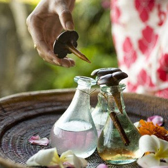 woman's hand holding a bottle stopper over aromatherapy bottles